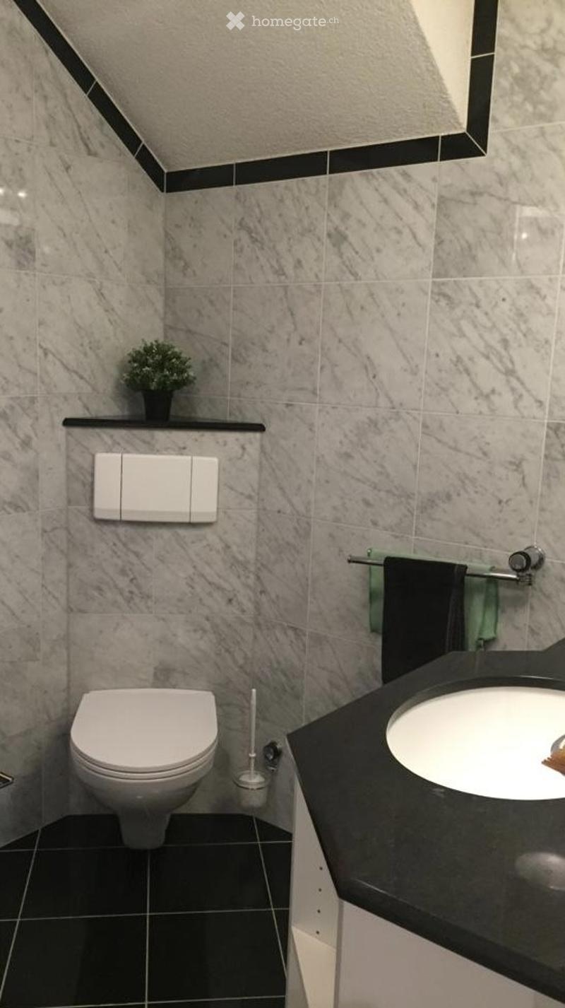 Compact bathroom with white toilet, marble tiles, and a sink with a faucet.