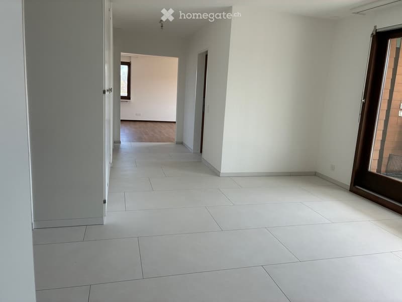 Empty hallway with white tiles, white walls, glass door, and a window.