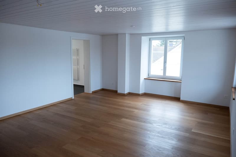 Empty room with white walls, wooden floor, and a window with a sill.