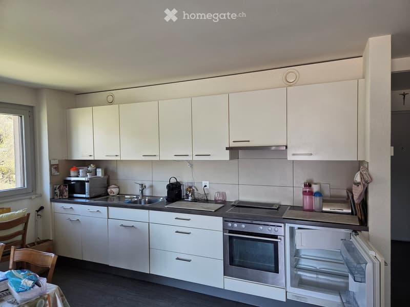 Kitchen. Modern kitchen with white cabinets, stainless steel appliances, and a central island. Includes a microwave, fridge, oven, sink, and various kitchen items.