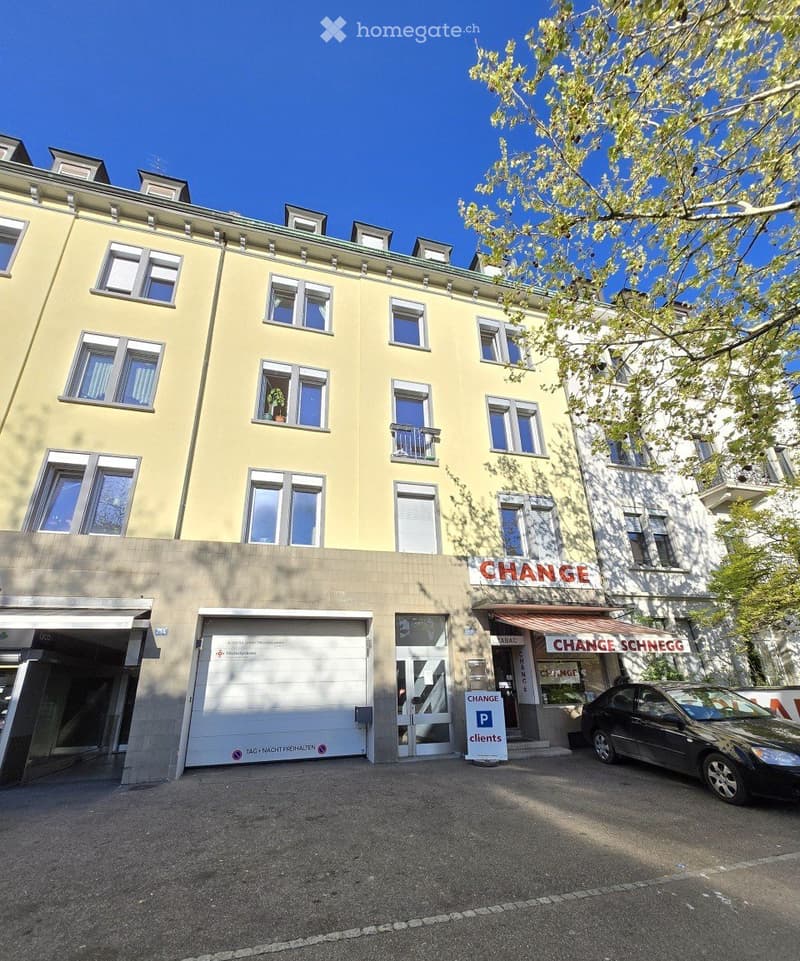 Four-story building with yellow facade, multiple windows, garage entrance, and signage for 'CHANGE' and 'CHANGE SCHNEGG'.