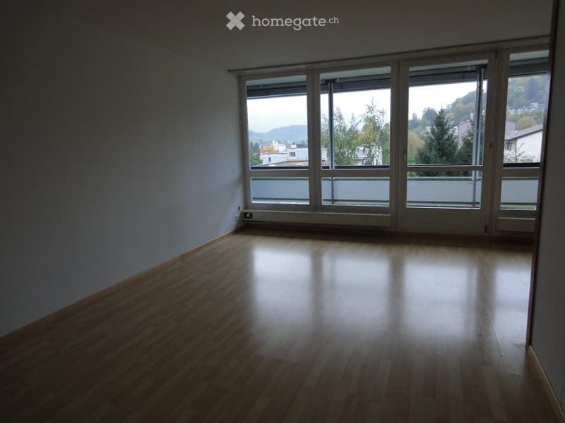 Unfurnished Room. Empty room with wooden flooring and large windows offering a view of trees and buildings outside.