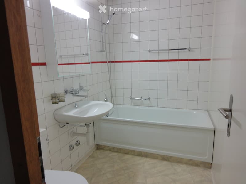 Bathroom. Modern bathroom with white tiled walls, a bathtub, a sink, a mirror, and a showerhead.