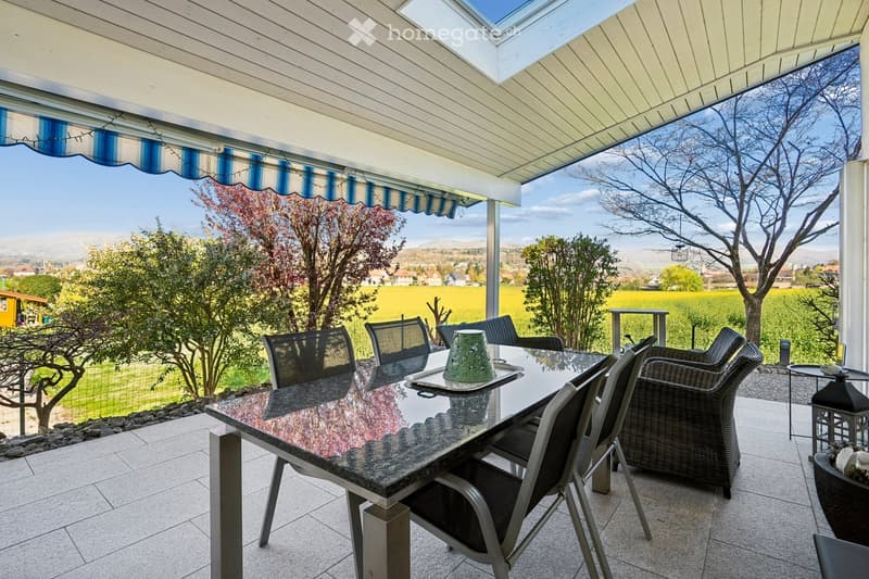 Outdoor dining area with a granite table, chairs, and a view of a field.