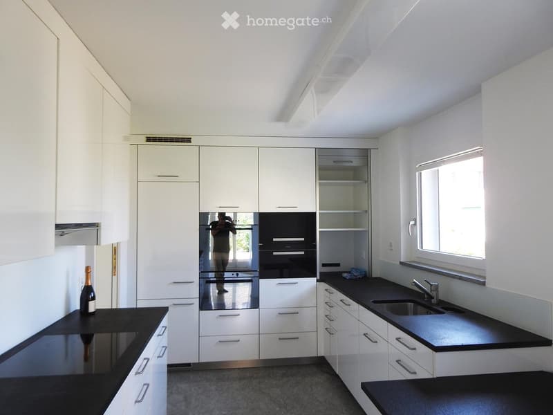 Modern kitchen with white cabinets, black countertops, stainless steel oven, and a sink with a faucet.