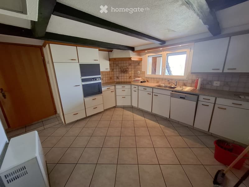 Kitchen. Bright kitchen with white cabinets, tiled floor, and modern appliances including an oven, sink, and dishwasher. Natural light from windows illuminates the space.