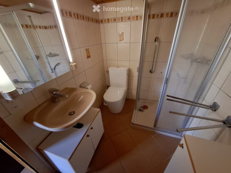 Bathroom. Bathroom with a sink, toilet, and shower area with a glass enclosure. The walls are tiled with a decorative border, and the floor is tiled in a light brown color.