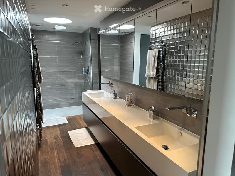 Bathroom. Modern bathroom with double sinks, large mirror, and tiled walls. Includes a shower and towel racks.