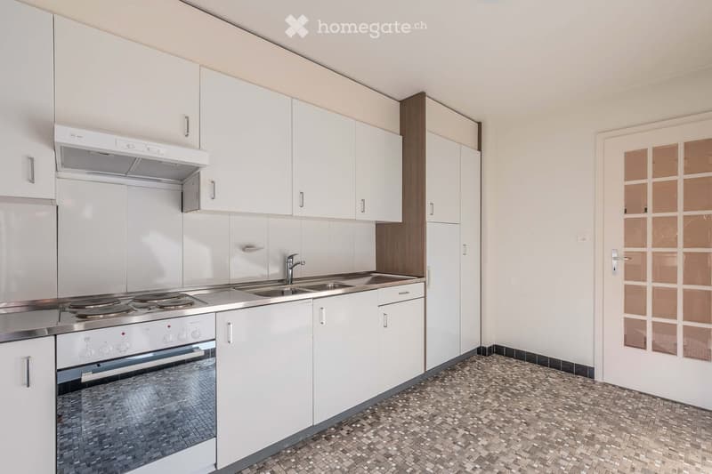 Modern kitchen with white cabinets, stainless steel appliances, and a mosaic tile floor.