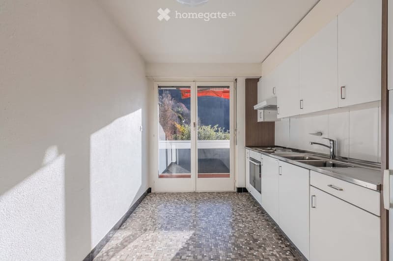 Modern kitchen with white cabinets, stainless steel sink, and a sliding glass door leading to a balcony.