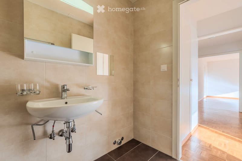 Modern bathroom with a white sink, chrome faucet, built-in mirror cabinet, and two glass cups on a shelf.