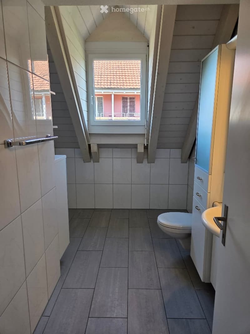 Bathroom with a toilet, shower, sink, white tiles and wood floor