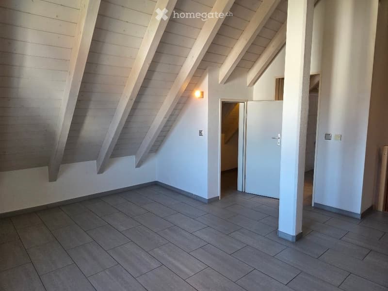 empty attic room with white wooden ceiling and tiled floor