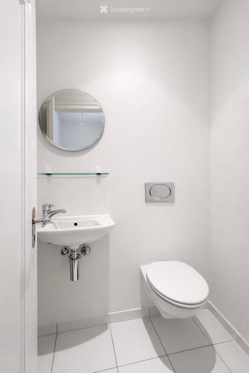 small bathroom with white tiles, white sink, mirror, toilet