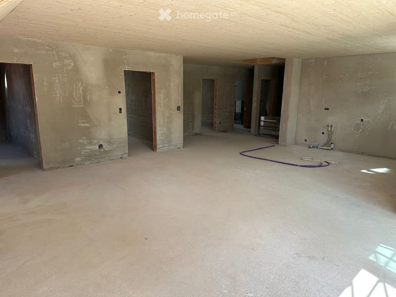 Unfurnished Room. Empty room with unfinished concrete floor and walls, exposed wooden ceiling, and several doorways leading to other spaces.