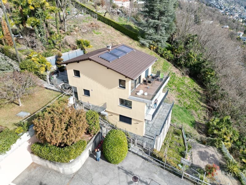 two story house, brown roof, solar panels, balcony, large driveway, garden