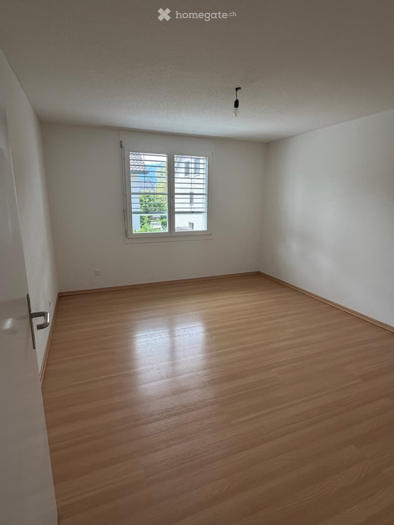Unfurnished Room. Empty room with wooden flooring, white walls, and a window with blinds. No furniture or equipment is present.