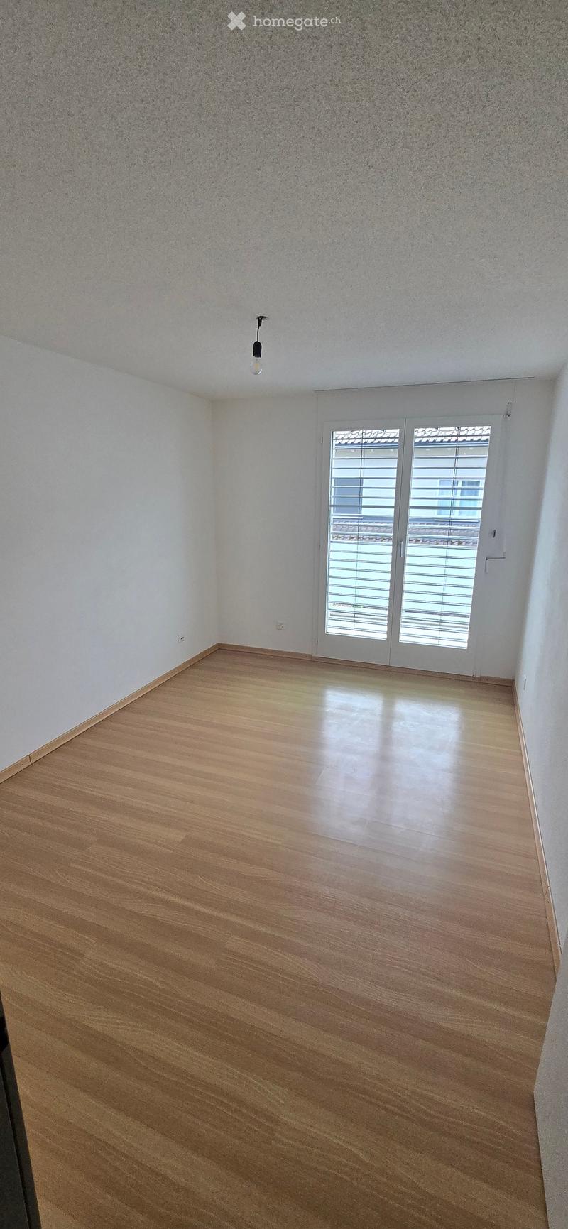 Unfurnished Room. Empty room with wooden flooring, white walls, and a large sliding glass door with blinds.
