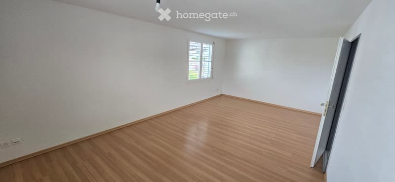 Unfurnished Room. Empty room with wooden flooring, white walls, and a single window with blinds. No furniture or equipment present.