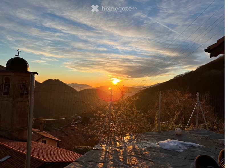 Balcony / Terrace. A scenic balcony or terrace view at sunset, overlooking a town with tiled roofs, a church tower, and distant mountains.