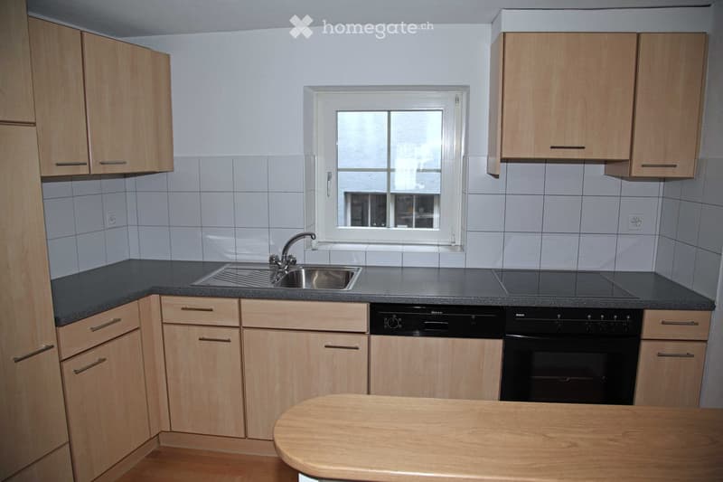 Modern kitchen with light wooden cabinets, stainless steel sink, dishwasher, and oven. Features a window above the sink and a wooden countertop.