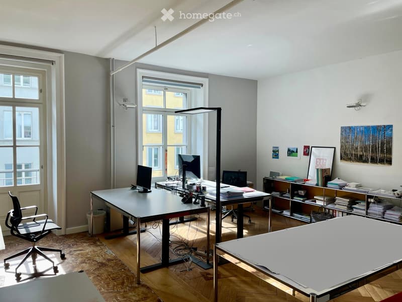 modern office room with two desks, monitors, office chairs, bookshelves, floor lamp, window