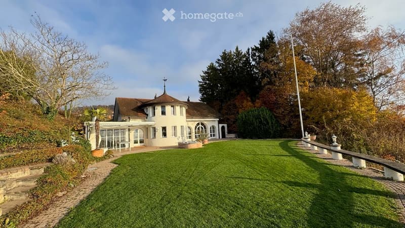 Garden / Outdoor Area. A well-maintained garden with a circular lawn, a modern house with large windows and a dome-shaped roof, and a pathway leading to the house.