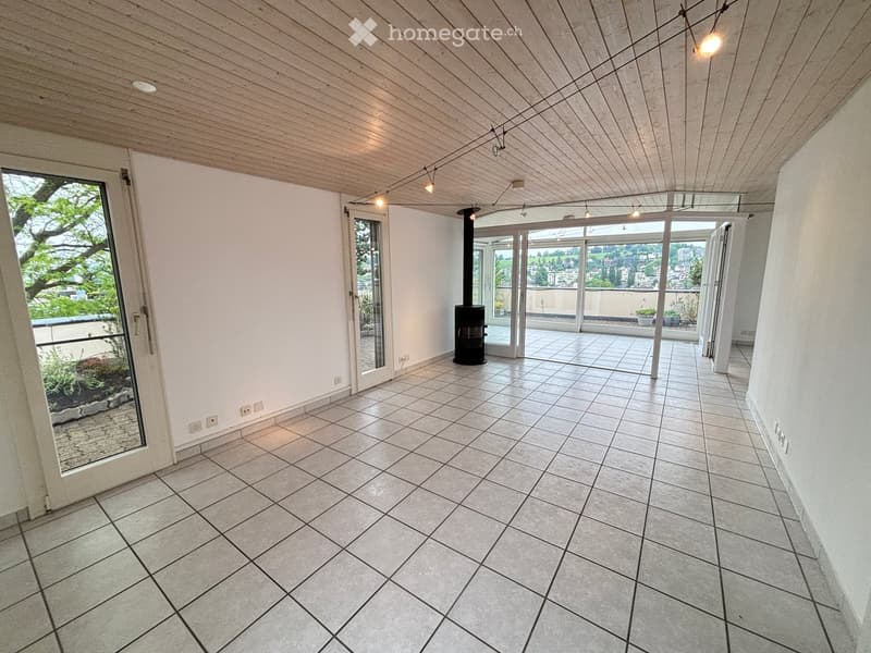 Empty room with tiled floor, white walls, wooden ceiling, and large glass doors leading to a balcony with outdoor space.