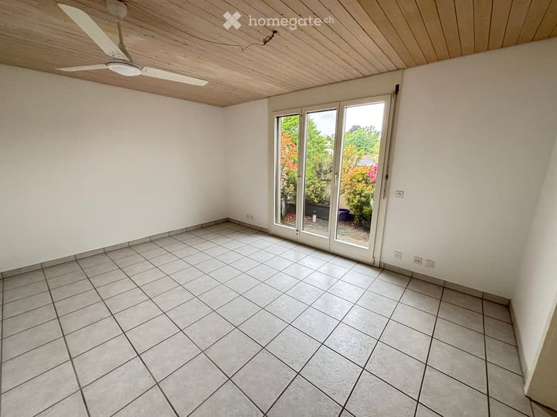 Empty room with tiled floor, white walls, and large sliding glass doors leading to an outdoor area.