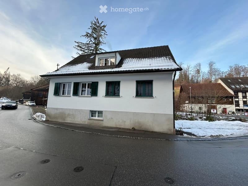2 story house, white walls, green shutters, brown roof, parked cars on the street