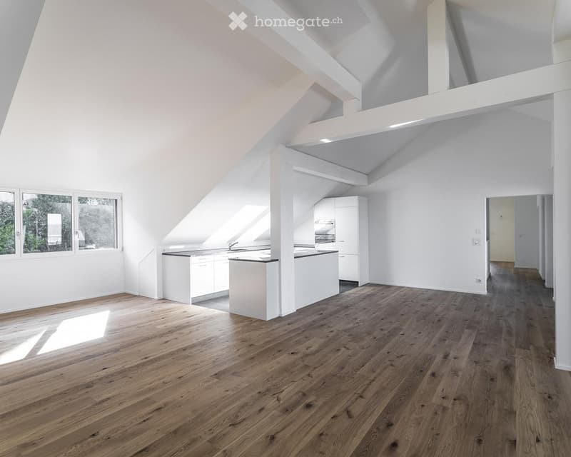 Spacious room with wooden floor, white walls, high ceiling, a kitchen area with cabinets and countertops, and a window.
