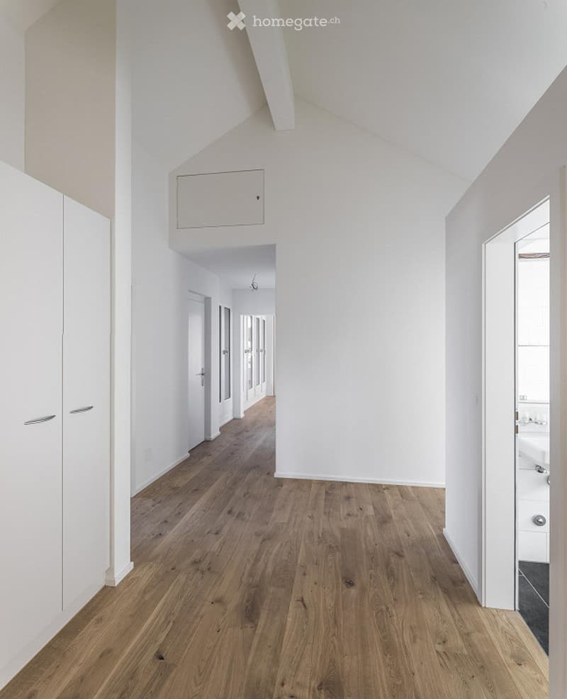 wooden floor, white walls, hallway leading to other rooms, white doors, slanted ceiling