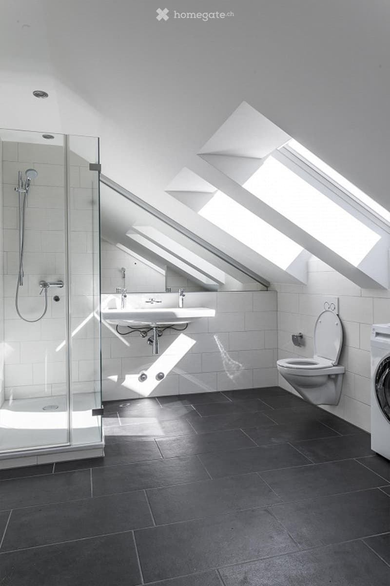 white tiled walls, black tiled floor, shower, sink, toilet, washing machine