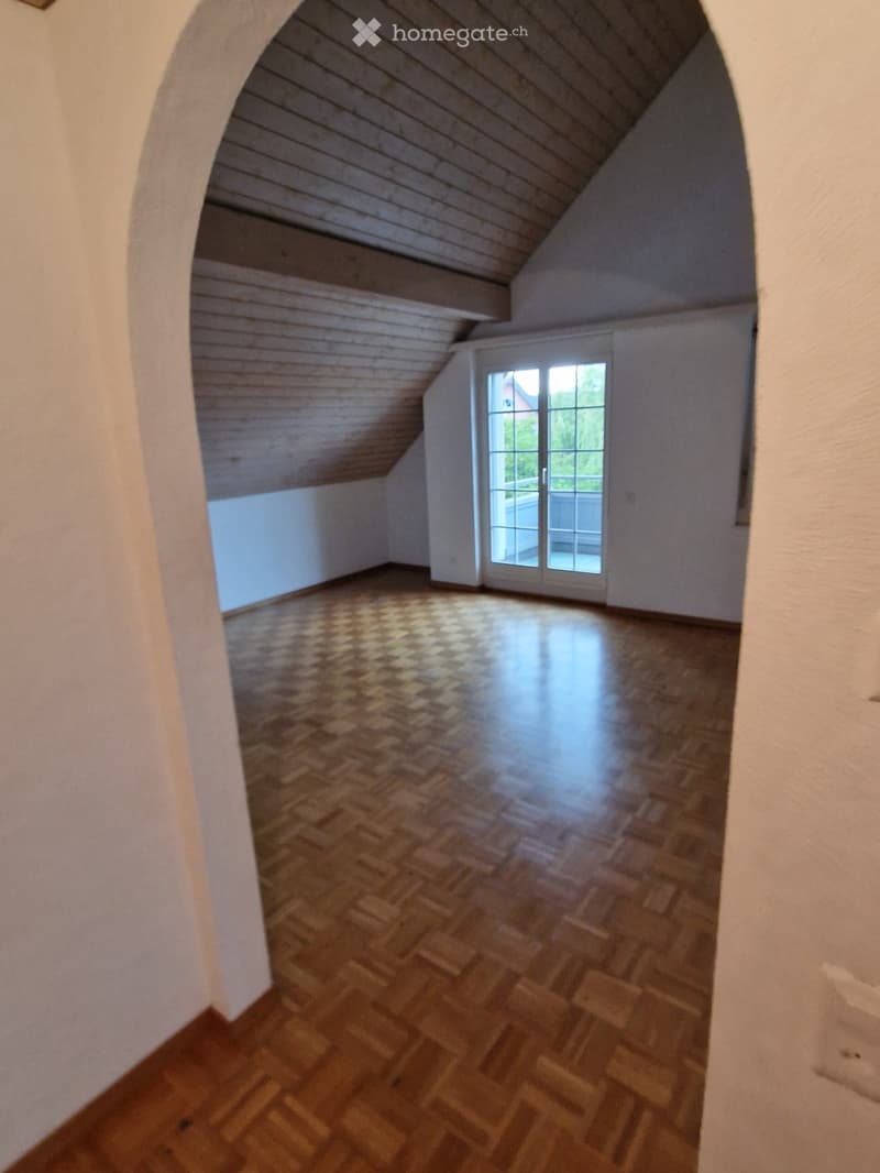 Empty room with wooden herringbone flooring, white walls, and a large window with glass panels leading to a balcony or terrace.
