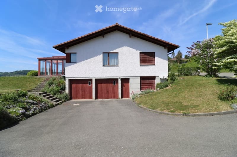 Two-story white house with red garage doors, a covered porch, and a well-maintained lawn.