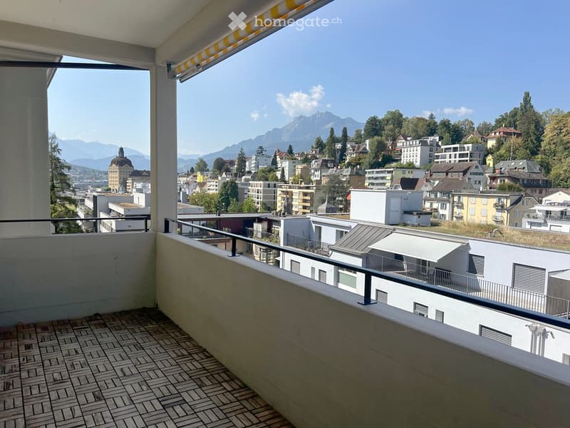 Balcony with tiled floor, metal railing, and scenic city and mountain view.