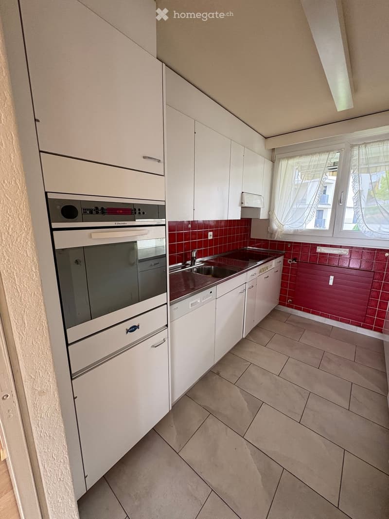 Kitchen with white cabinets, red tiles, tiled floor, stainless steel sink, dishwasher, oven, tiled backsplash