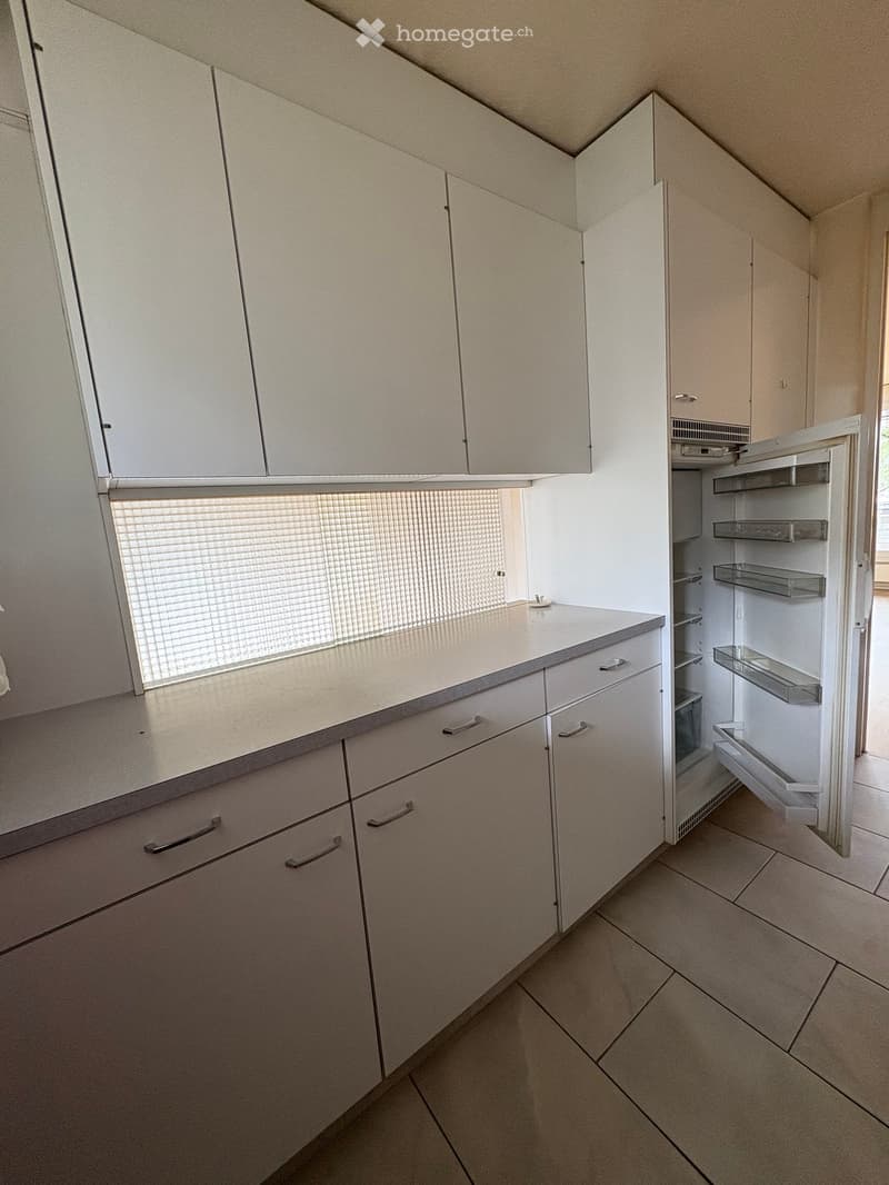kitchen with modern white cabinets, tiled countertop, open refrigerator, light flooring