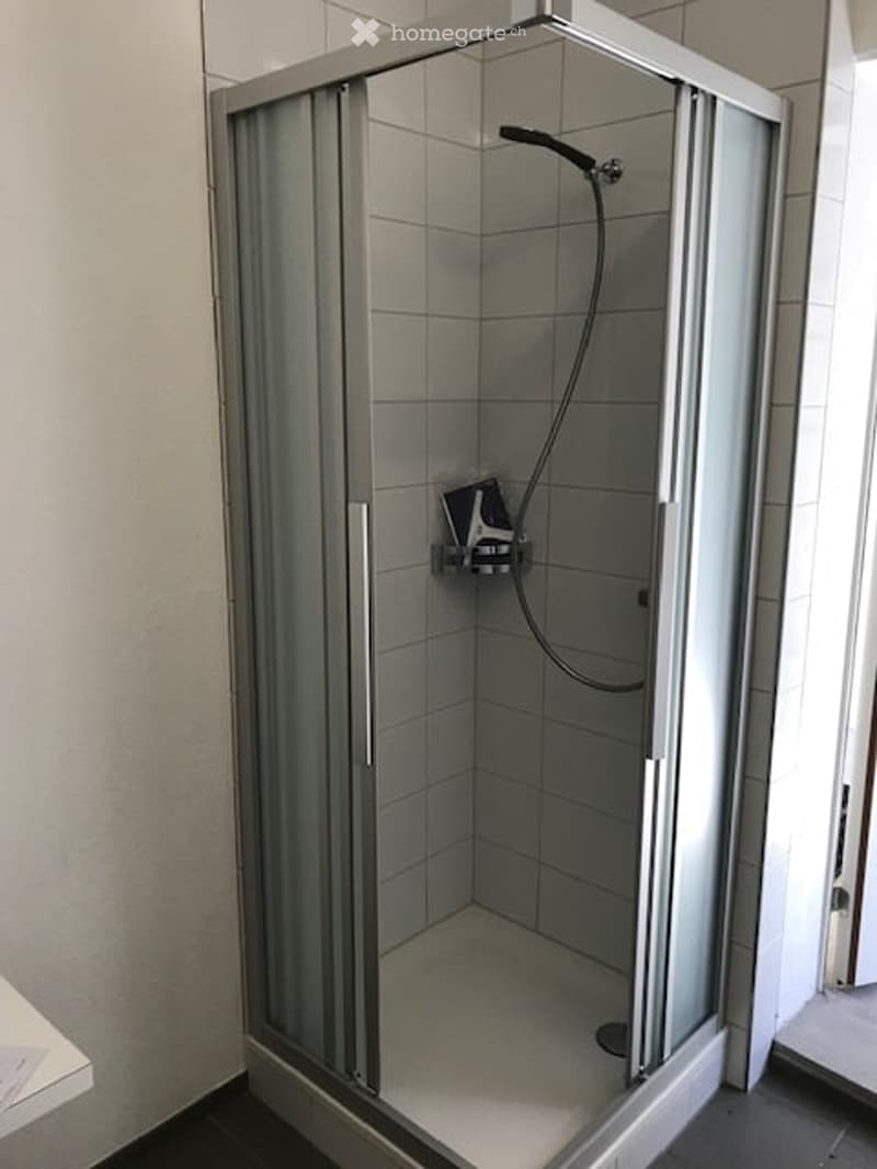 shower stall with glass doors, white tiles, shower head, and a soap holder