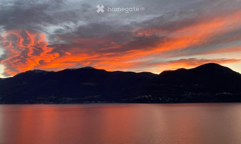 A landscape with mountains and a lake under a colorful sunset