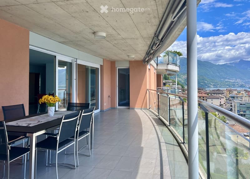 Balcony with dining table, vase of flowers, glass railings, tile floor