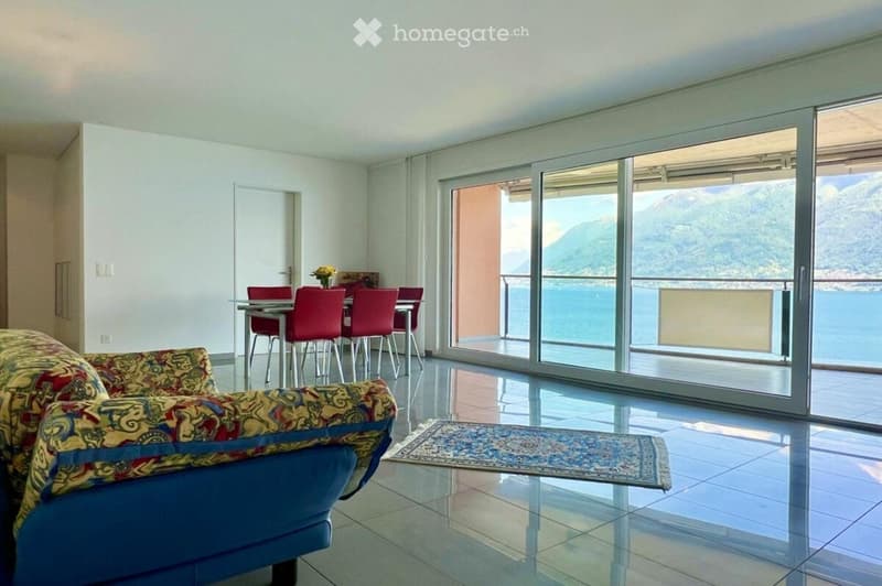 spacious living room with blue couch, dining table, and sea view balcony