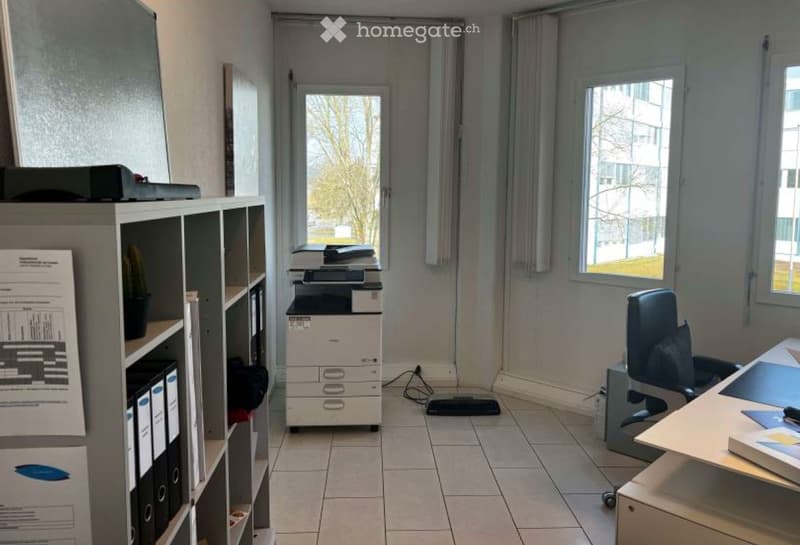 Furnished Room. Office space with tiled floor, large windows, office chair, desk, printer, cabinet, and filing cabinet.