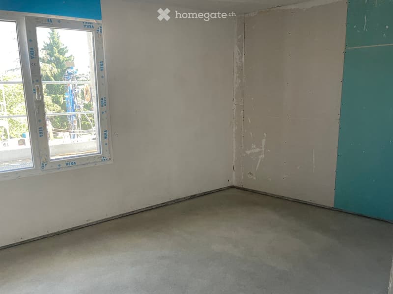 Empty room with bare walls and a concrete floor, featuring a single window with protective film.