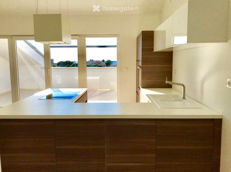 Kitchen. Modern kitchen with white countertops, dark wooden cabinets, a sink, and a view of the outdoor area through large windows.