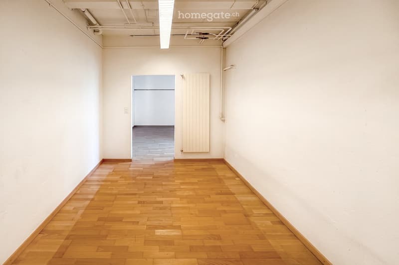 Unfurnished Room. Empty room with wooden flooring and white walls, featuring a radiator and a doorway leading to another space.