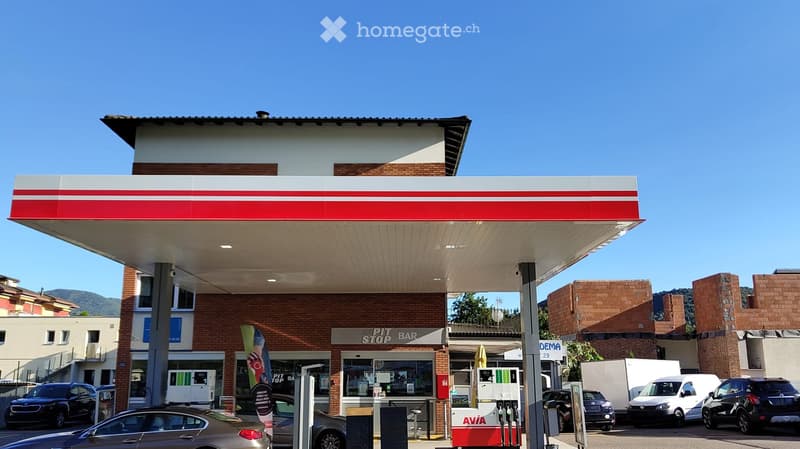 Building. Gas station with a canopy, brick building, and several parked cars.