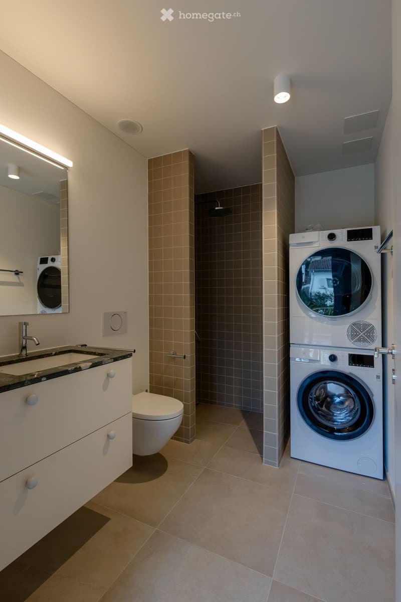 Laundry room with a washer dryer and sink with mirror.