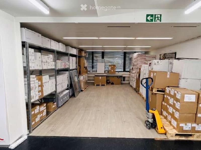 Furnished Room. A storage area with metal shelving units filled with boxes, a hand truck, and a desk with office supplies.