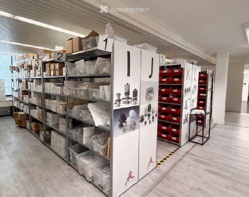 Furnished Room. A storage room with multiple metal shelving units filled with boxes, storage bins, and miscellaneous items. A small stool is placed near the shelves.